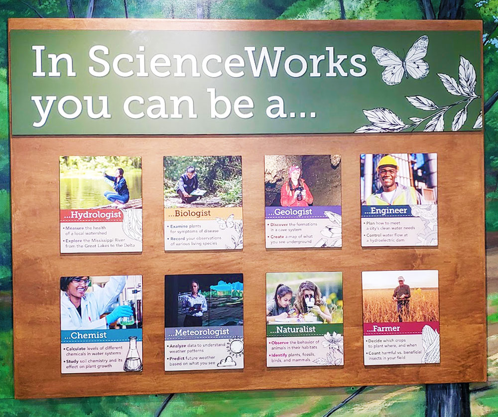 Sign in front of the Corteva Agrisciences ScienceWorks exhibit with photos of people of all genders who work in these careers: hydrologist, biologist, geologist, engineer, chemist, meteorologist, naturalist, or a farmer.